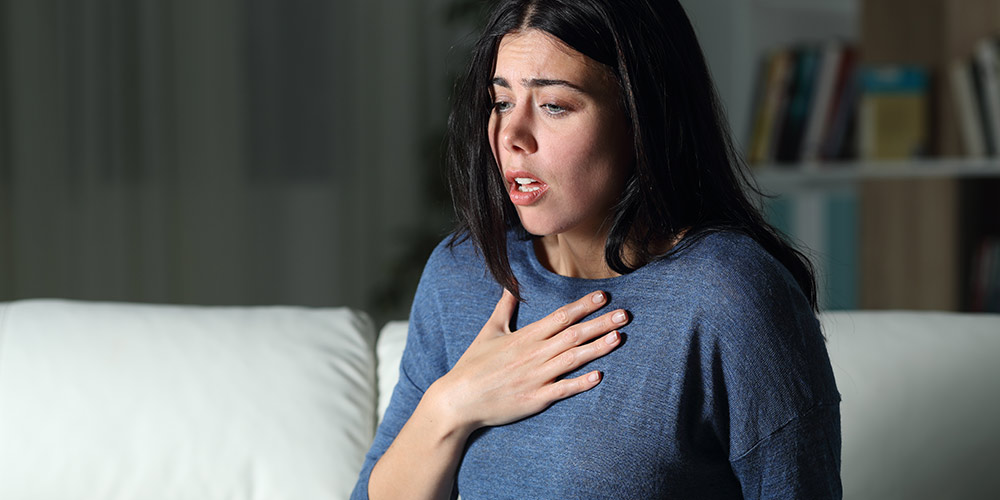 Woman holding her chest as she's experiencing anxiety