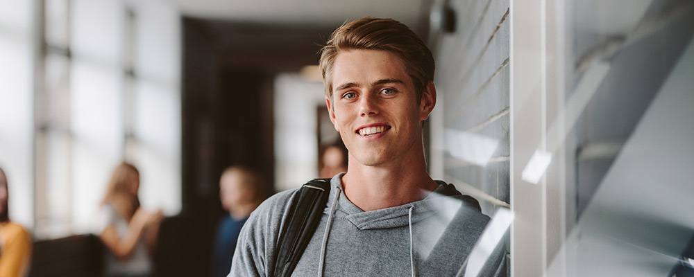 Teenager in a school corridor smiling at the camera
